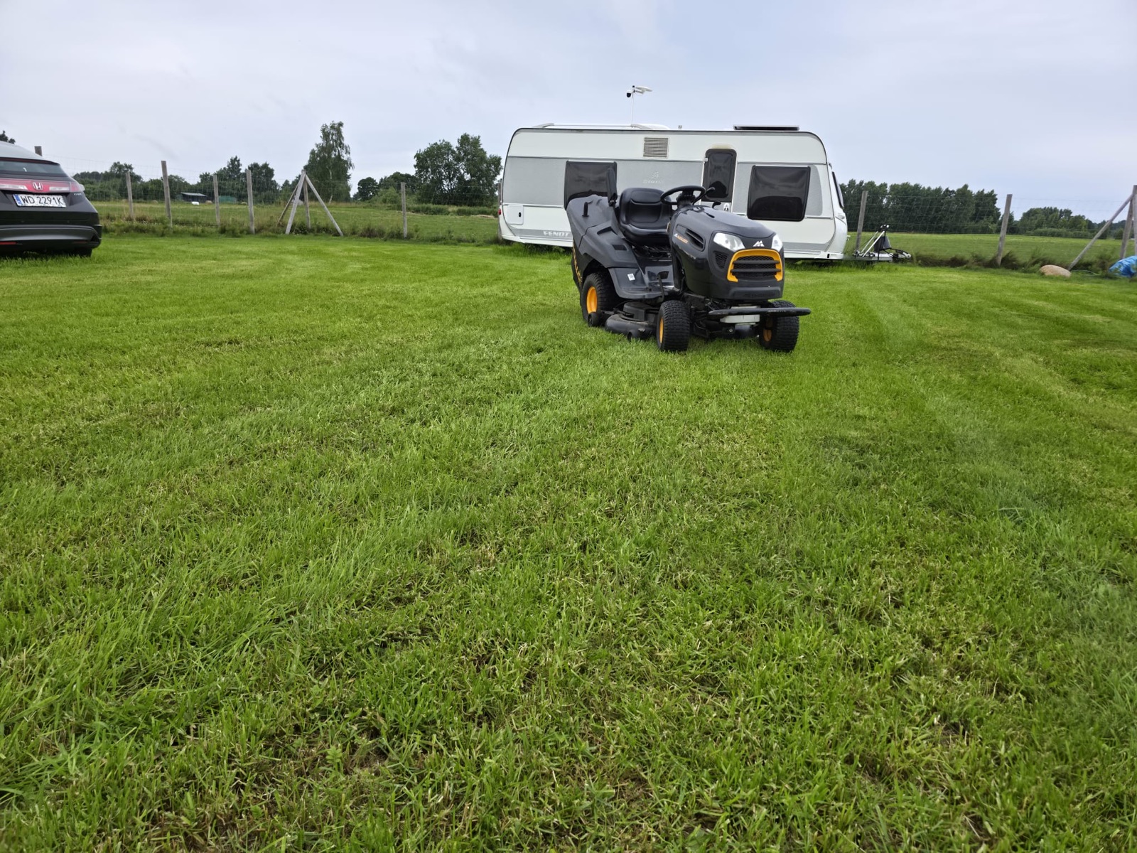 Traktorek koszący trawę przy przyczepie kempingowej